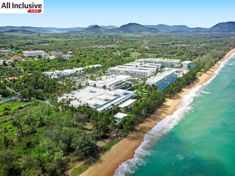 Blick auf den Strand im Hitergrund das Hotel mit vielen Palmen